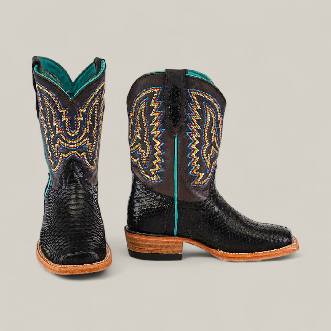 A pair of Exotic Python Black - Square Toe Kids Boots in trendy black python-textured leather with tan soles and vibrant blue, yellow, and orange stitching—one boot shown forward, the other sideways.
