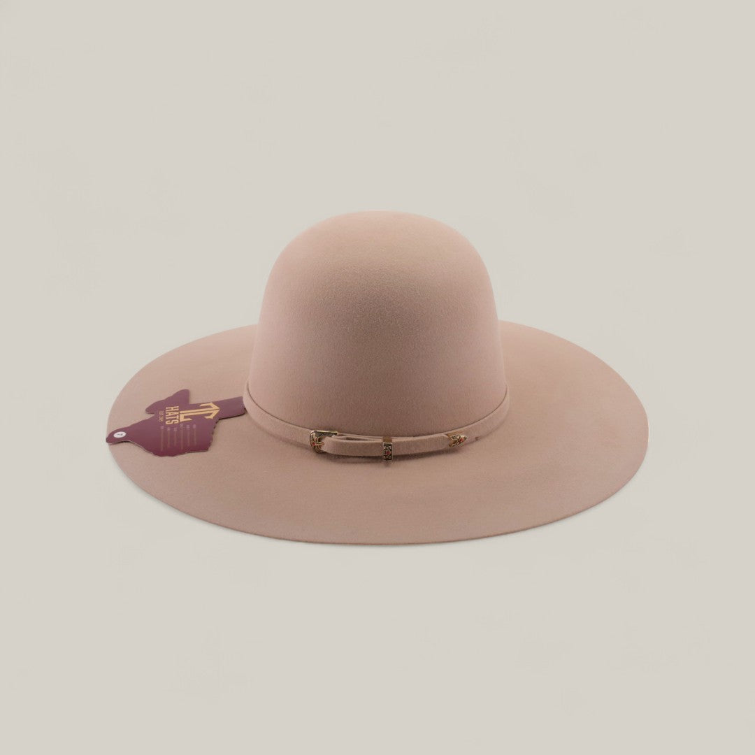 The 4X - Belly - TC Hats is a wide-brimmed, light beige Western hat with a shapeable crown, a thin band with small gold accents, and a purple tag on the left side. It is displayed against a plain, light-colored background.