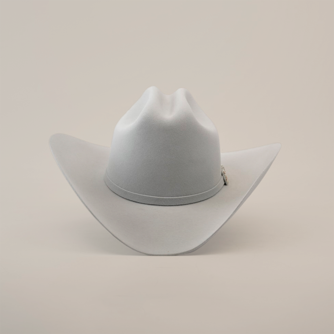 The 10X Jerarca Platinum, a gray fur felt cowboy hat with a wide brim and center crease, exudes classic western style. Its subtle hatband complements the design, reminiscent of Larry Mahans style, and is shown upright against a plain white background.