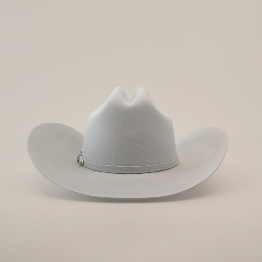 The 10X Jerarca Platinum, a light gray fur felt cowboy hat from the Larry Mahan collection, features a wide brim and a pin on the band, photographed against a plain white background.