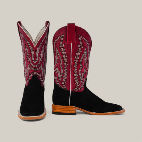 A pair of cowboy boots with black lower sections, tan soles and heels, and maroon shafts featuring intricate white and maroon stitching, displayed against a plain background.