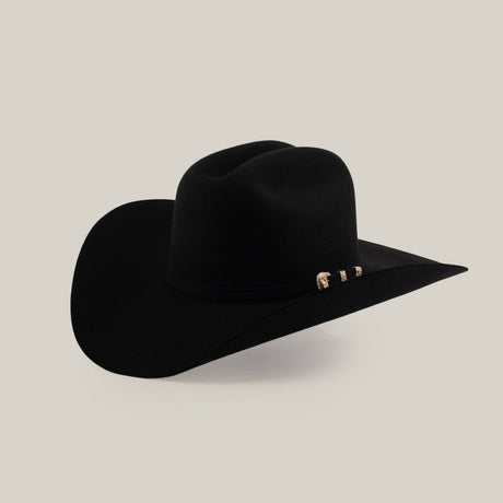 A black cowboy hat with a wide brim and decorative gold accents on the band, set against a plain gray background.