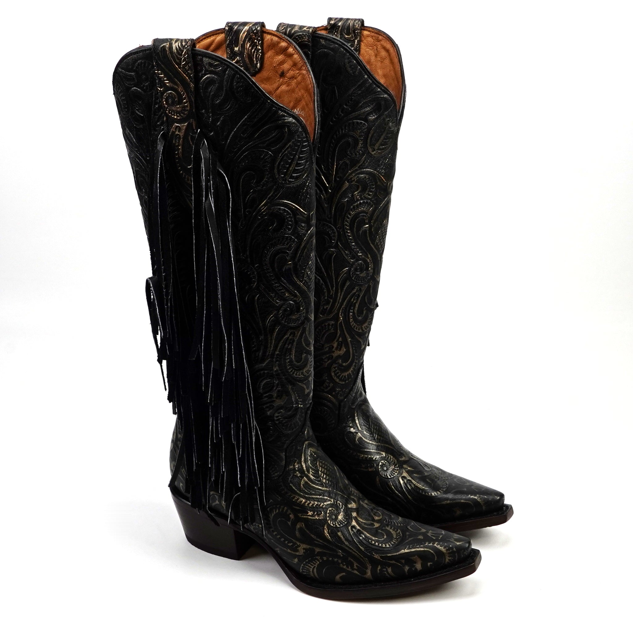 Pair of black cowboy boots with intricate designs and fringes on a white background