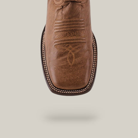 The Sierra Cinnamon - Square Toe boot is a brown cowboy boot with premium leather craftsmanship and intricate toe stitching, suspended against a light, neutral background. This Western-style boot showcases a square toe and detailed embroidery.