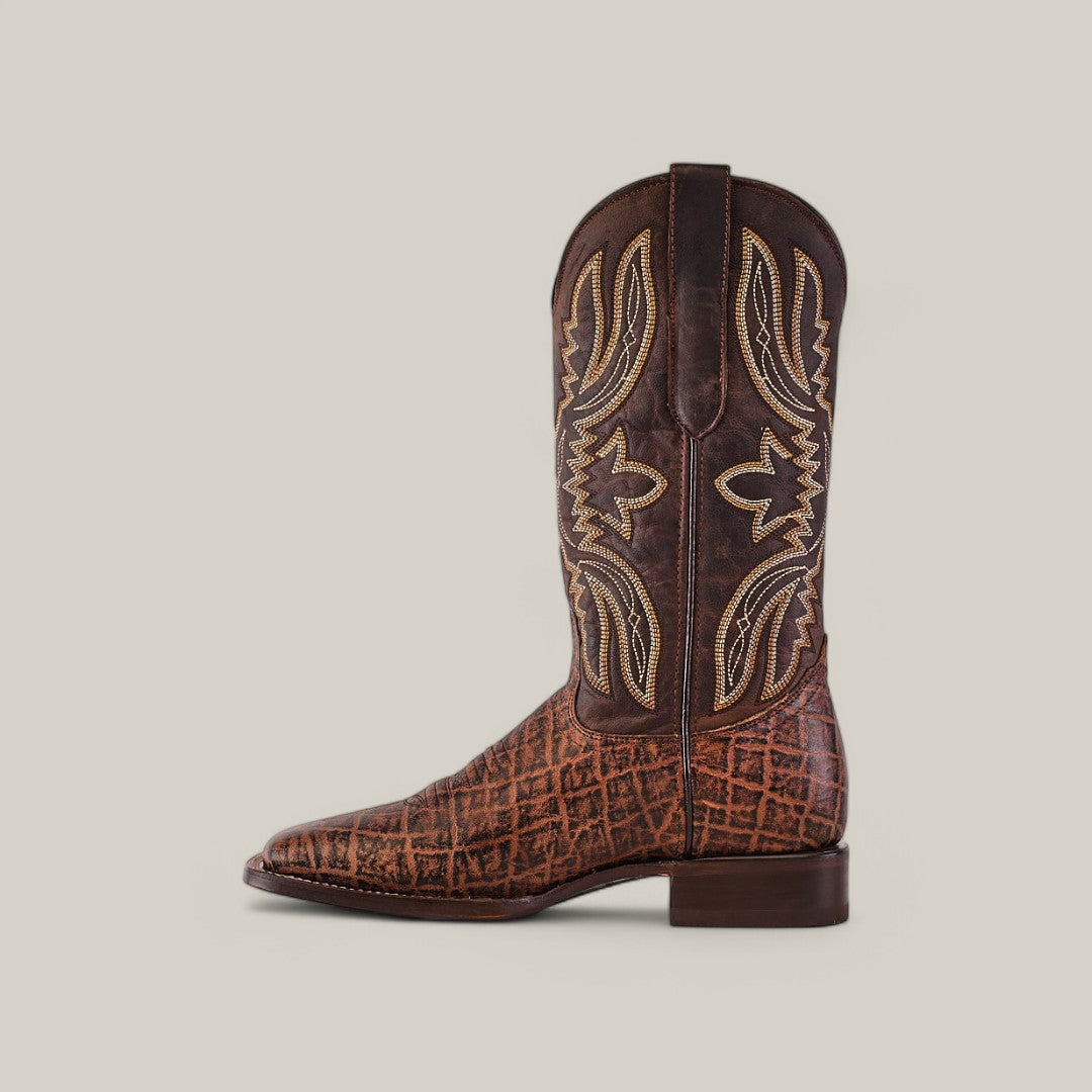 The Mamut Grimm Brown - Square Toe cowboy boot, crafted from premium leather, boasts intricate yellow embroidery on its shaft. It is displayed elegantly against a plain light gray background, featuring a slightly angled heel.