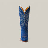 The Miranda Suede Blue Jeans Leather Sole boot showcases a vibrant blue single snip toe design with intricate white embroidery, a sturdy brown leather sole, and stands upright against a plain light grey background.