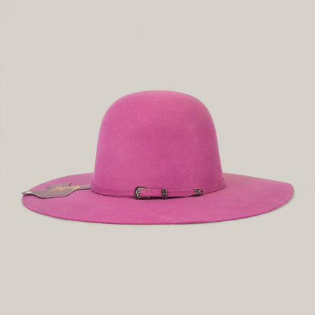The 4x Pink - TC Hats is a hot pink felt Western hat with a wide brim, open crown Texana style, and a small band at the base. A tag hangs on one side. The background is plain and light-colored.