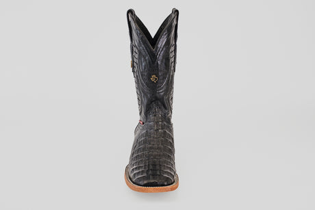 A single Exotic Caiman Horn Back boot in black with a square toe, tan sole, and decorative stitching, photographed from the front against a plain white background.