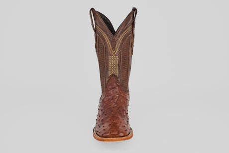 A single Exotic Full Quilt Ostrich - Brown - Square Toe boot made of textured leather with intricate stitching and a patterned toe and shaft, reminiscent of ostrich boots, is shown from the front against a plain light background.