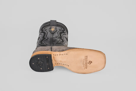 The Tanner - Matte Gray - Square Toe boots feature one upright and one on its side to display the Texas Country-branded sole, with a decorative stitched upper and textured Python Gris Nobuck lower section.