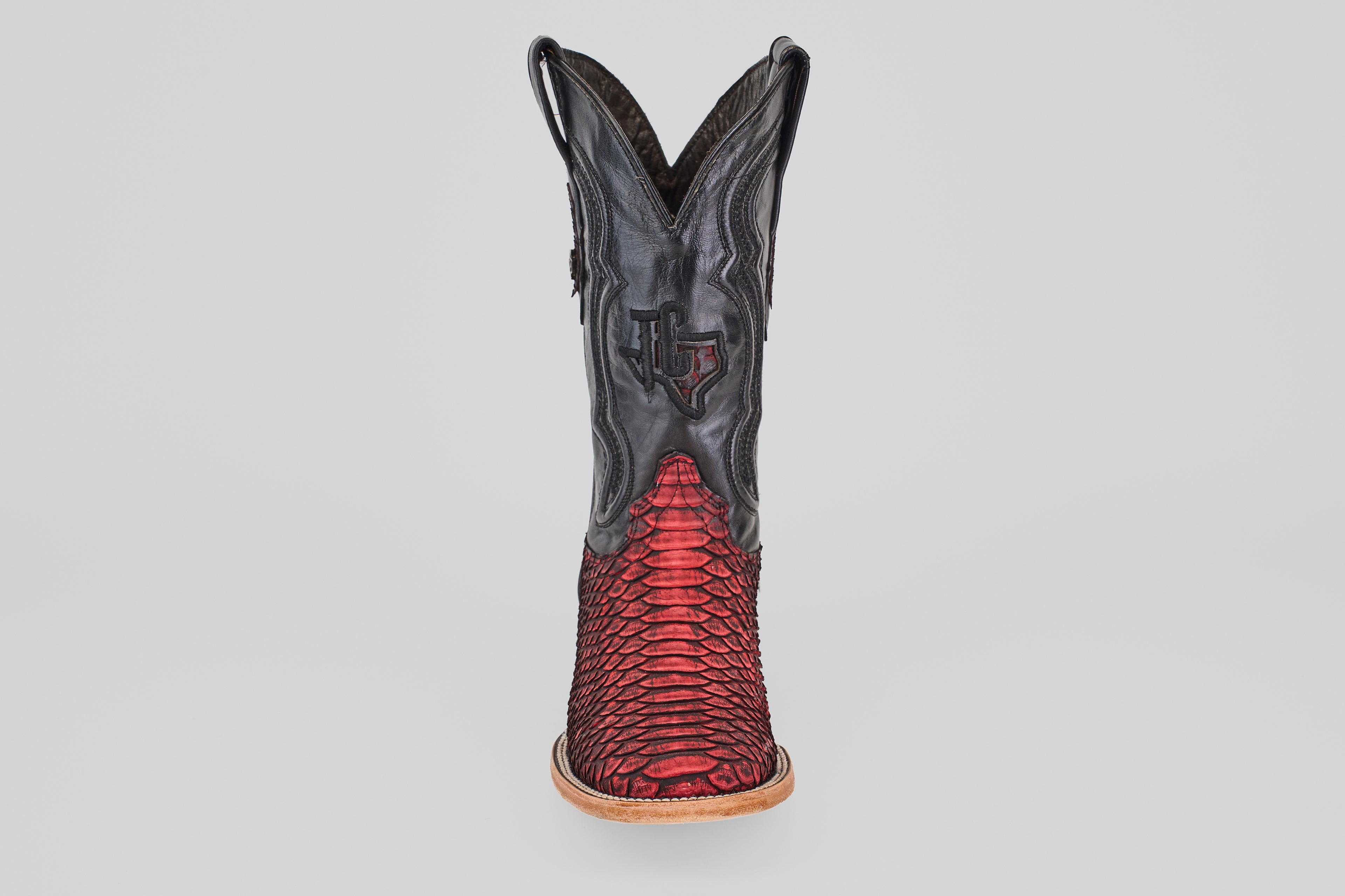 The Tanner – Scarlet – Square Toe is a western cowboy boot with a black upper and red python leather lower, detailed stitching, light brown sole, and square toe, shown from the front against a plain background.