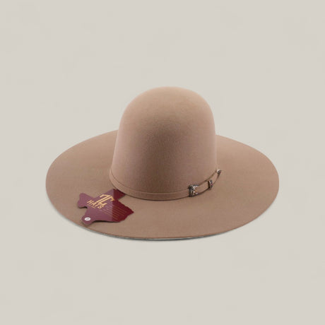 The 4x - Natural - TC Hats features a wide-brimmed, light brown felt design with a decorative band and buckle, plus a maroon tag, shown on a neutral background.