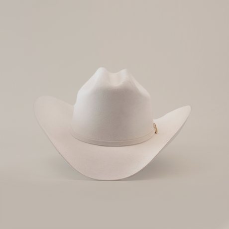 The 6X Real White is a luxury Western cowboy hat with a wide brim and creased crown, handcrafted by artisans from fur felt. It is elegantly displayed against a plain white background.