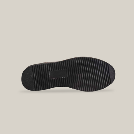 The image displays the sole of a black shoe with outstanding craftsmanship. The thick, textured pattern boasts horizontal grooves for enhanced traction and durability, similar in quality to a Brown Roper - Laredo Sole - Soft Toe. Lighting emphasizes the depth of the treads beautifully.