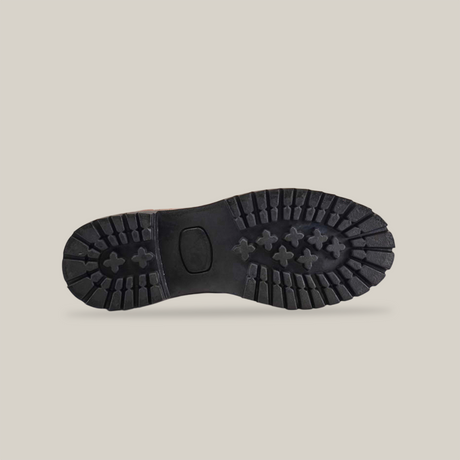 The image features the Brandy Roper - Tractor Sole - Soft Toe boot, showcasing a black rugged sole with deep treads, a central oval shape, and cross-like grooves on a plain white background.