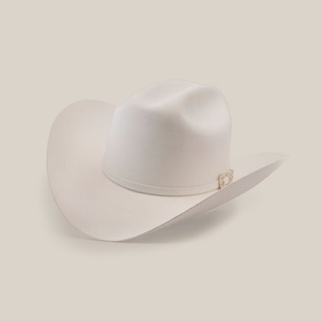The 10X Jerarca White is a beige cowboy hat made from fine fur felt, featuring a wide brim and a decorative band around the crown. This classic western headwear, reminiscent of Larry Mahan 10X style, is presented against a plain white background.