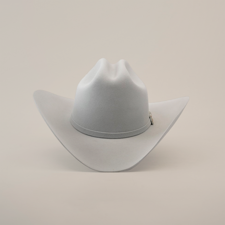 The 10X Jerarca Platinum, a gray fur felt cowboy hat with a wide brim and center crease, exudes classic western style. Its subtle hatband complements the design, reminiscent of Larry Mahans style, and is shown upright against a plain white background.